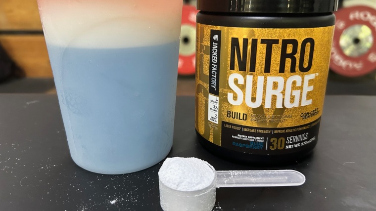 A scoop of NitroSurge Build next to a shake and the container