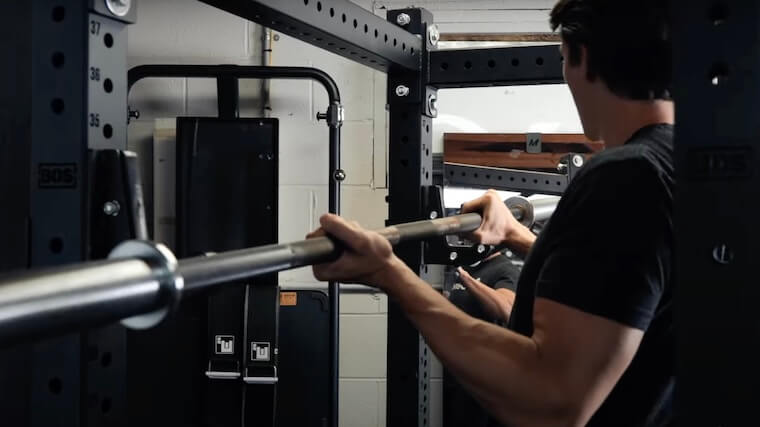 Our tester placing a barbell on the Bells of Steel Hydra Rack.