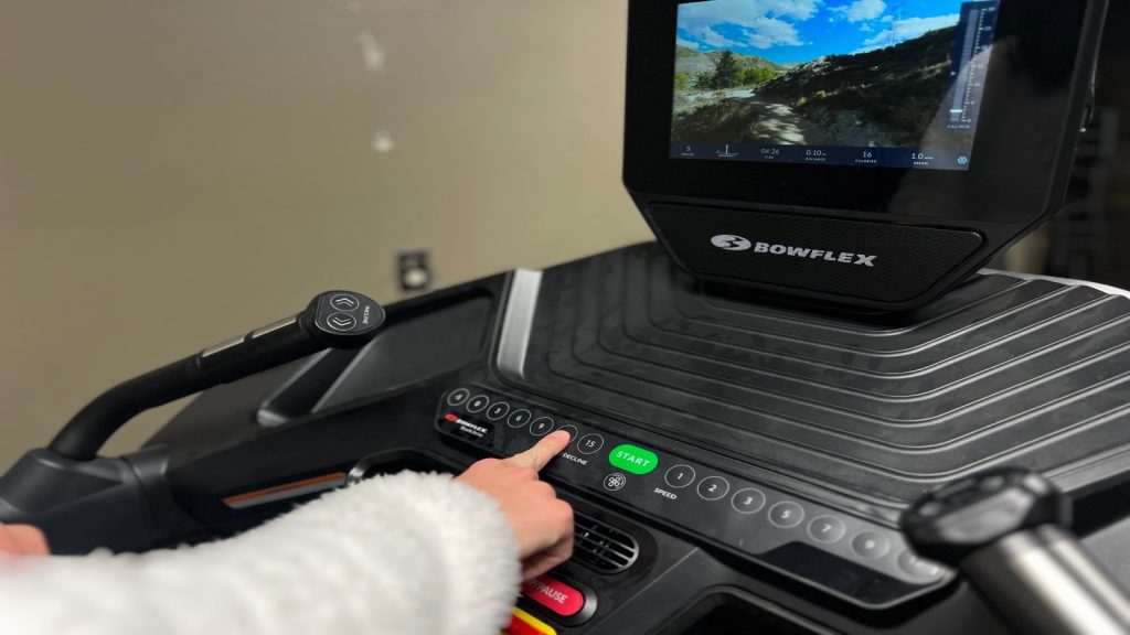 Our BarBend product tester adjusting the controls on the console of the Bowflex Treadmill 10.