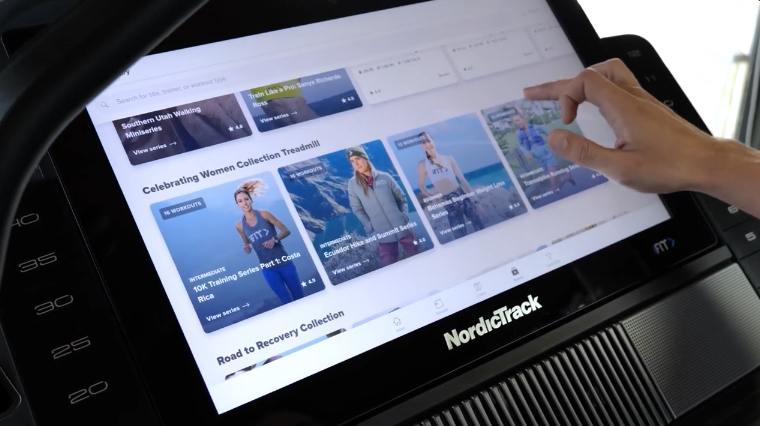 A hand can be seen browsing iFit on the NordicTrack Commercial X22i.