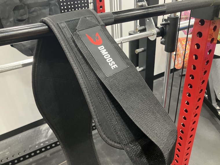 The DMoose 2-In-1 Neoprene Weightlifting Belt hanging over a barbell.