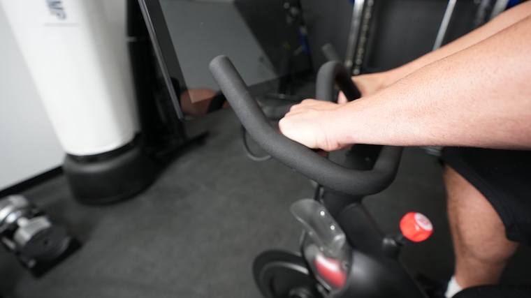 Our tester gripping the bullhorn-style handlebars of the Original Peloton Bike