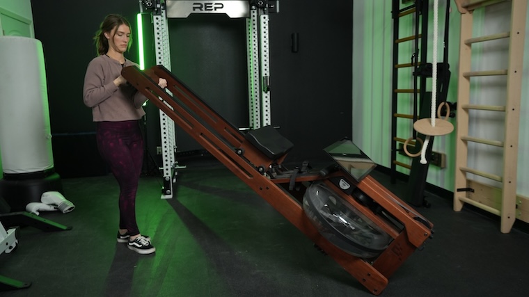 Our tester moving the Ergatta Rower into position for a workout