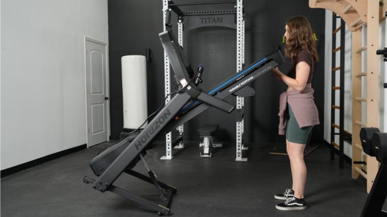 A person lifting the foldable deck of the Horizon 7.0 AT Treadmill