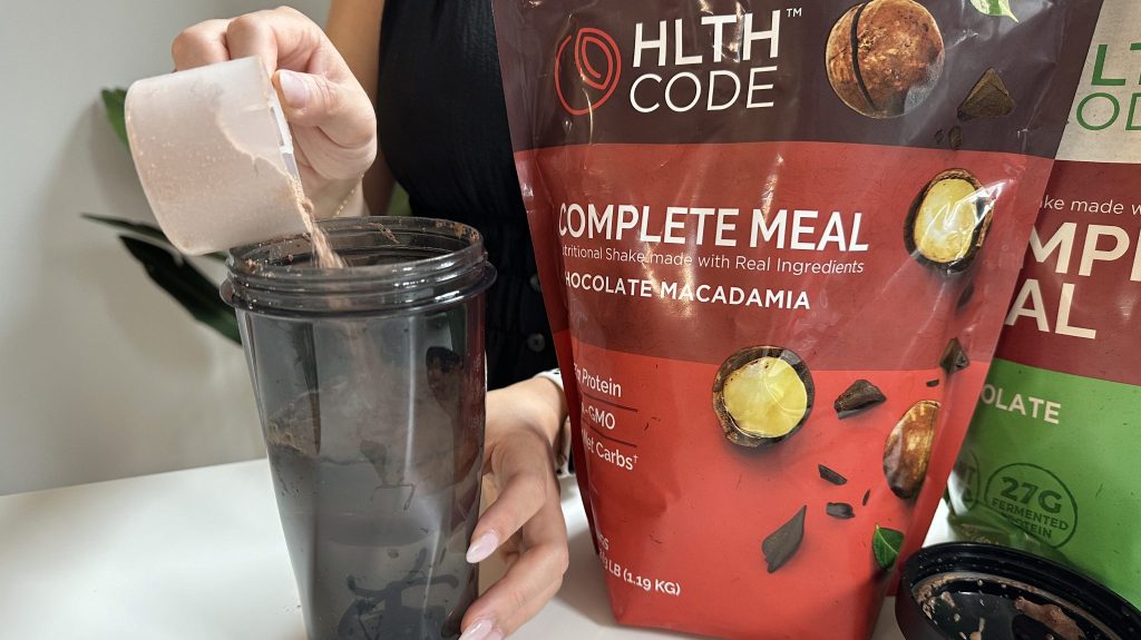 Our tester scooping the HLTH Code Meal Replacement powder into blender bottle.