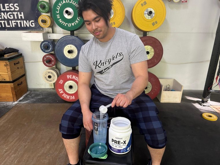 Our tester pouring a scoop of Nutricost Pre-Workout.