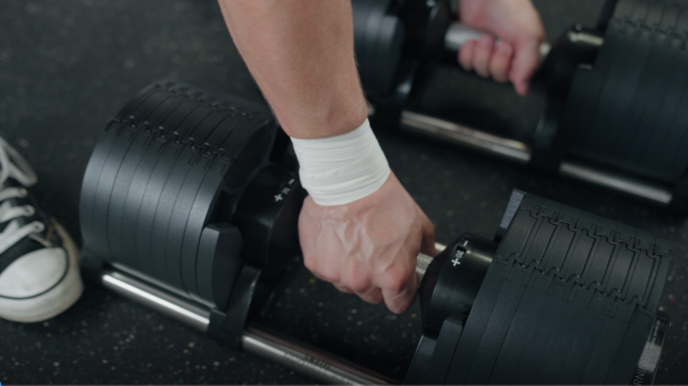 Removing the NÜOBELL Adjustable Dumbbells from their cradle.