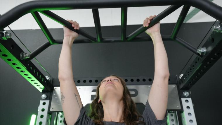 a woman gripping a pull up bar and looking up