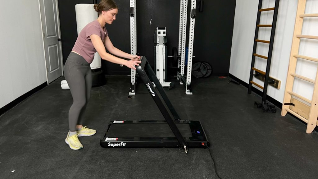 Our BarBend product tester holding the adjustable handlebar on the Goplus 2-in-1 Folding Treadmill.