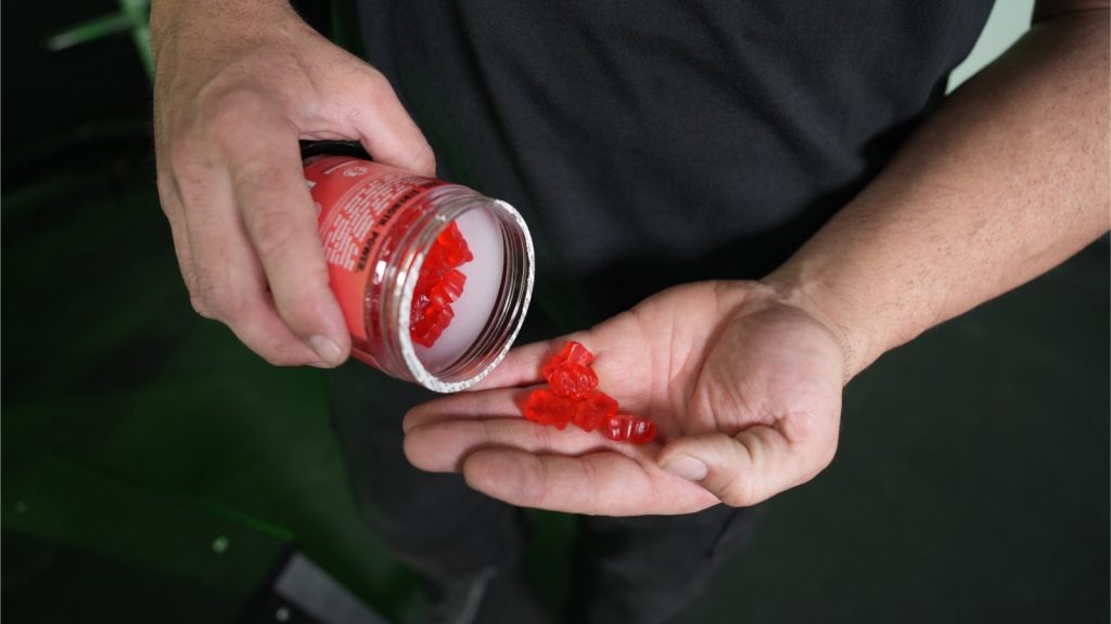 A person holds a handful of red Swoly Creatine Gummies.