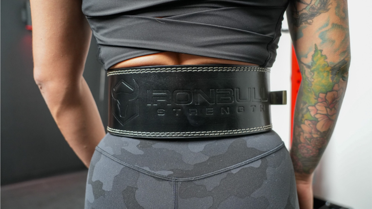 A person wears an Iron Bull weightlifting belt.