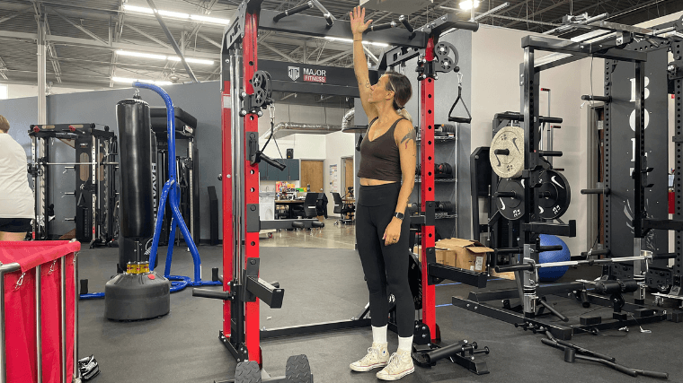 A woman demonstrates how tall the Major Fitness Raptor 22 is with her outstretched hand.