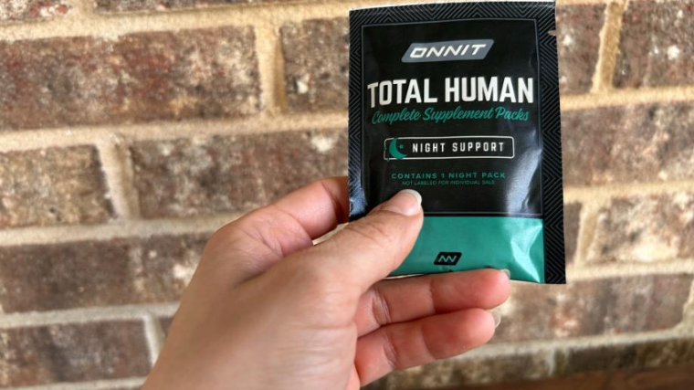 A person holds a packet of Onnit Total Human multivitamins.