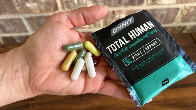 A person holds some Onnit Total Human mulivitamins in their hand.