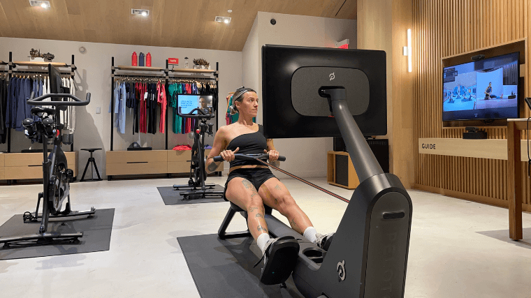 A woman uses the Peloton Row at a Peloton showroom.