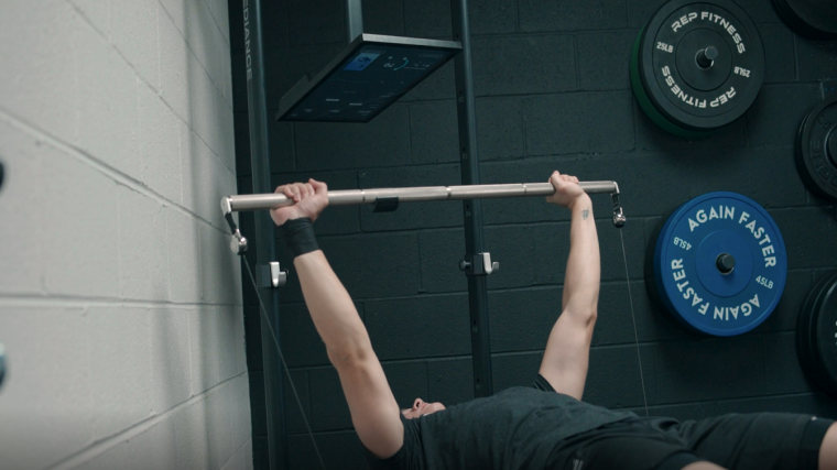 A BarBend tester bench-pressing using the Speediance home gym.